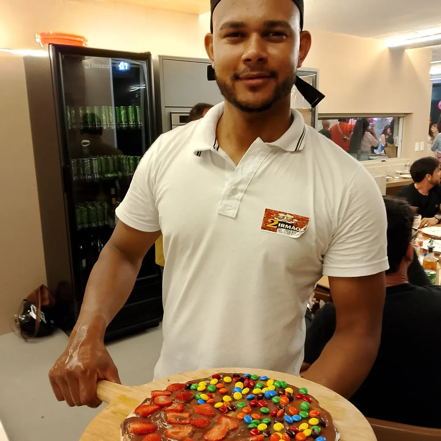 Funcionário da Pizzas Dois Irmãos apresentando uma pizza doce